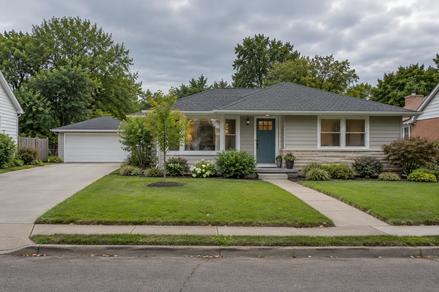 Suburban lot seen from the street with a house, a detached garage, a concrete driveway and a walkway